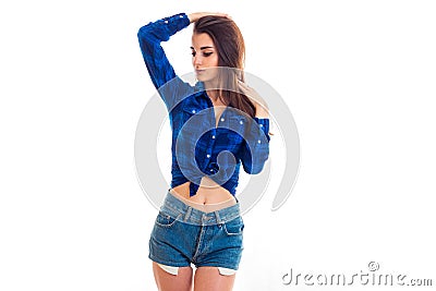 Beautiful young girl`s shirt in the box and in denim shorts looks away and raised her hand to head Stock Photo