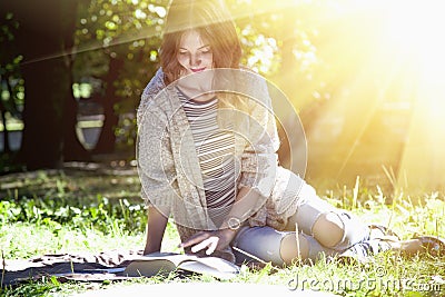 Beautiful young girl siting on the grass and reading a book edu Stock Photo