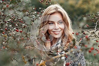 Beautiful young girl with a smile in a warm scarf near a tree Stock Photo