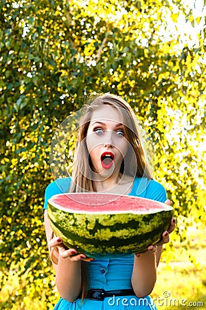 Beautiful young girl stares at the half of juicy watermelon Stock Photo