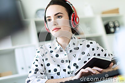 Beautiful young girl sitting in headphones at desk in office. Photo with depth of field, focus on girl. Stock Photo