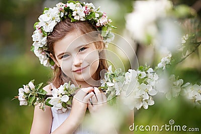 Beautiful young girl in white dress in the garden with blosoming apple trees. Cute girl holding apple-tree branch Stock Photo