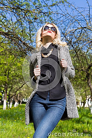 Beautiful young happy blonde girl in coat, jeans and sunglasses Stock Photo