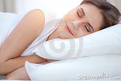 Beautiful young and happy woman sleeping while lying in bed comfortably and blissfully smiling Stock Photo