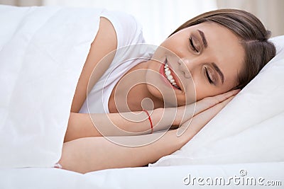 Beautiful young and happy woman sleeping while lying in bed comfortably and blissfully smiling Stock Photo