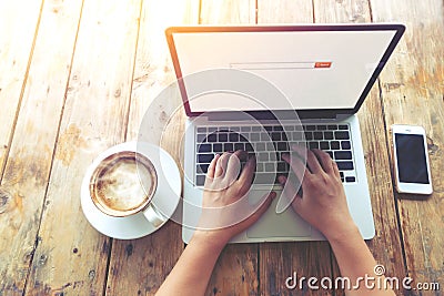 Beautiful young hipster woman`s hands busy working on her laptop sitting at wooden table in a coffee shop Stock Photo