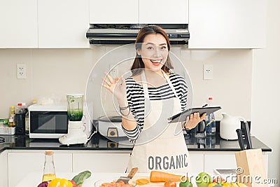 Beautiful young housewife woman with tablet computer cooking in Stock Photo