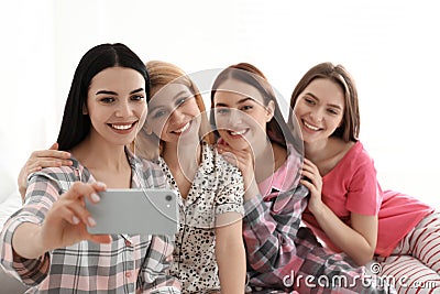 Beautiful ladies taking selfie on bed at pamper party. Women`s Day Stock Photo