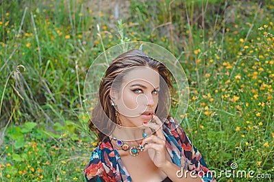 Beautiful young lady in fancy necklace sitting in Stock Photo