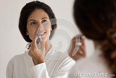 Beautiful young latina woman look at large mirror paint lips Stock Photo