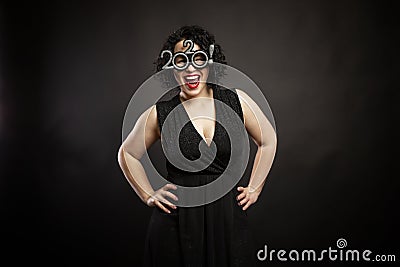 Beautiful young laughing woman in new year glasses. Curly brunette. Black background Stock Photo