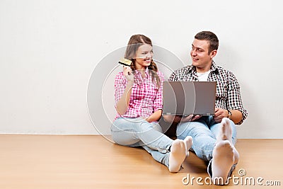 Beautiful young loving couple shopping online while sitting on the floore together Stock Photo