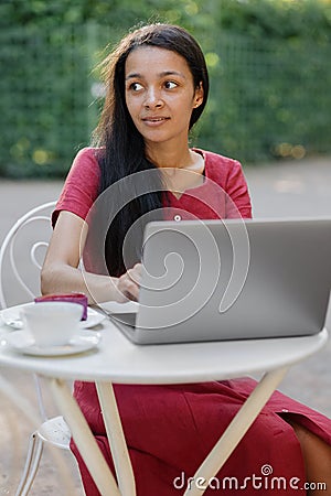 Beautiful and young millennial African woman in a public place working on a laptop Stock Photo