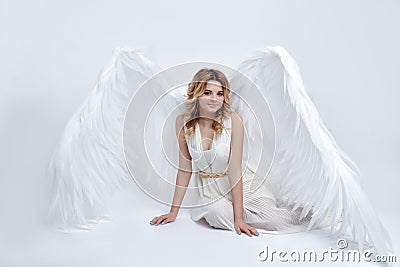 Beautiful young model with big angel wings sitting in the studio Stock Photo