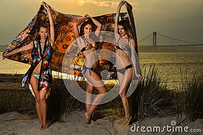 Beautiful young models wearing bikinis posing at sunset beach. Stock Photo