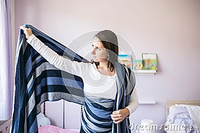 Beautiful young mother wrapping sling for baby around her Stock Photo