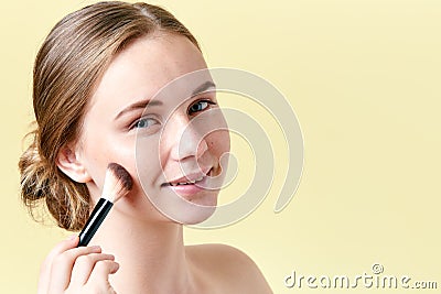 Beautiful young redhead woman with freckles contouring her cheekbones with make up brush. Beauty portrait Stock Photo