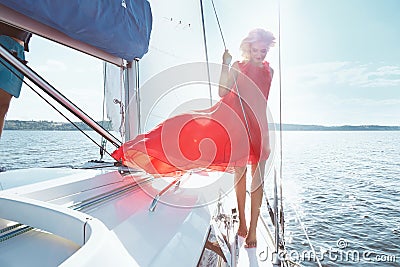 Beautiful young brunette girl in a dress and makeup, summer trip on a yacht with white sails on the sea or ocean in the Gulf Stock Photo