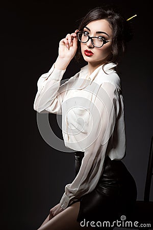 Beautiful young business woman with dark updo hair looking direct over her trendy glasses in modern frame. Stock Photo