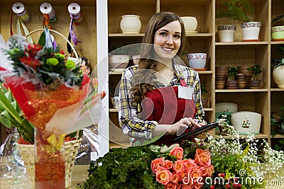 Beautiful young smilling woman florist are using a tablet in flower shop Stock Photo
