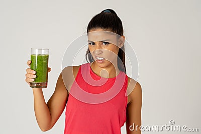 Beautiful young sport woman tired of diet holding green smoothie in dislike Stock Photo