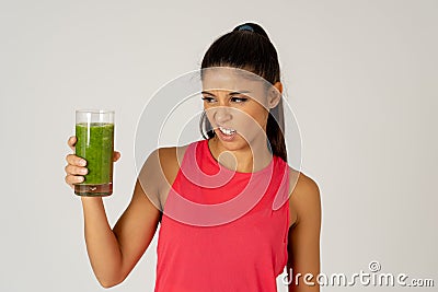 Beautiful young sport woman tired of diet holding green smoothie in dislike Stock Photo