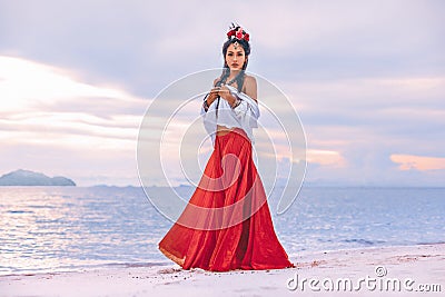 Beautiful young stylish boho woman walking on the beach at sunset Stock Photo