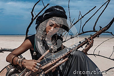 Beautiful young stylish tribal woman in oriental costume playing Stock Photo