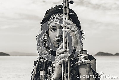 Beautiful young stylish tribal woman in oriental costume playing sitar outdoors. Close up Stock Photo