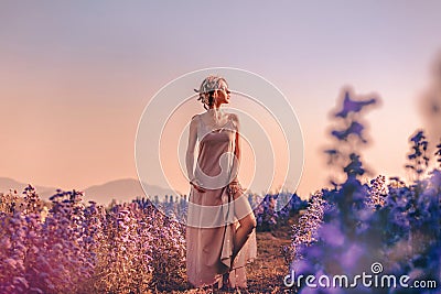 Beautiful young stylish woman posing on the field at sunset Stock Photo