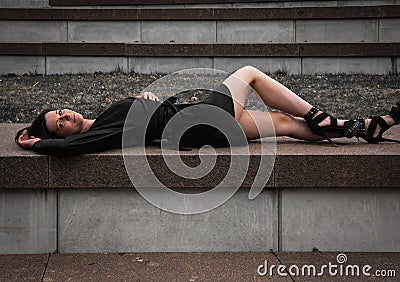 Beautiful young svelte sexy attractive German female model posing on the wall in a black dress Stock Photo