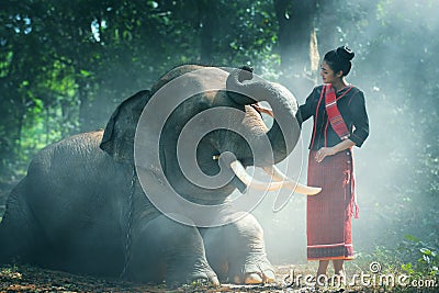 Beautiful young Thai woman northeast style is enjoy dancing and playing with elephant in the jungle Stock Photo