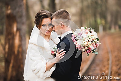 Beautiful young wedding couple posing with bouquet of flowers in hands Stock Photo