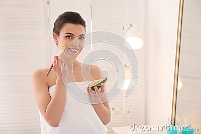 Beautiful young woman applying avocado facial mask in bathroom Stock Photo