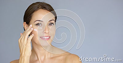 Beautiful young woman applying face cream Stock Photo