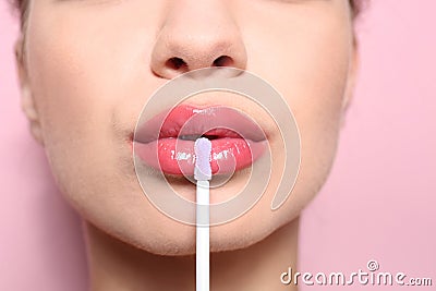 Beautiful young woman applying gloss on her perfect lips Stock Photo