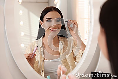 Beautiful young woman applying makeup near mirror Stock Photo