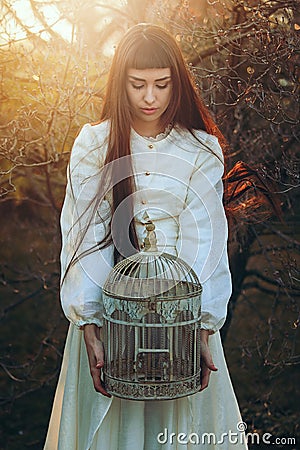 Beautiful young woman with bird cage Stock Photo