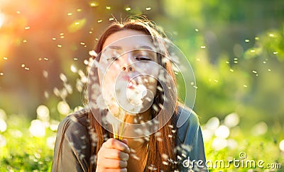 Beautiful young woman blowing dandelions Stock Photo