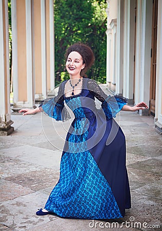 Beautiful young woman in blue medieval dress doing curtsey Stock Photo