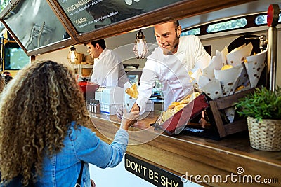 Beautiful young woman buying barbecue potatoes on a food truck. Stock Photo