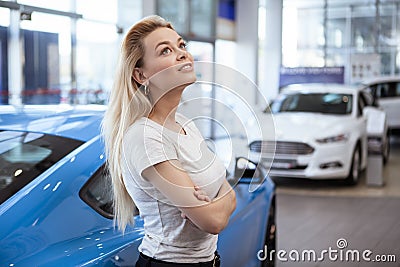 Beautiful young woman buying new car at the dealership Stock Photo