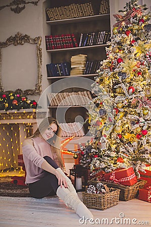 Beautiful young woman in a Christmas interior. Dressing a Christmas tree. Stock Photo