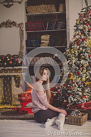 Beautiful young woman in a Christmas interior. Dressing a Christmas tree. Stock Photo