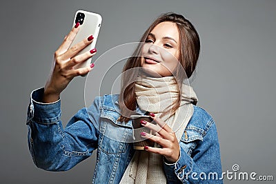 Beautiful young woman drinking coffee and looking at the phone screen Stock Photo