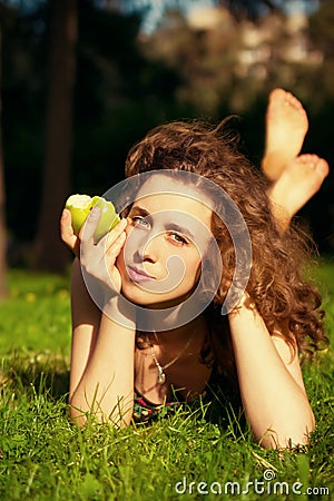 Beautiful young woman eating apple outdoors Stock Photo