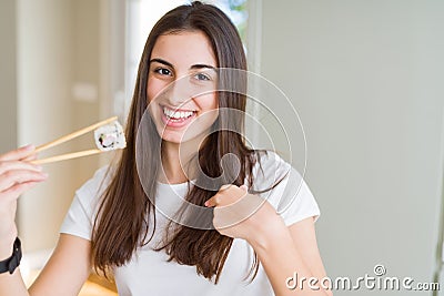 Beautiful young woman eating asian sushi using chopsticks with surprise face pointing finger to himself Stock Photo