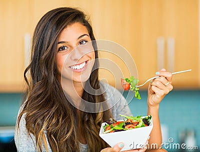 Beautiful young woman eating a bowl of healthy organic salad Stock Photo