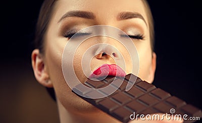 Beautiful young woman eating dark chocolate. Beauty girl enjoying chocolate Stock Photo