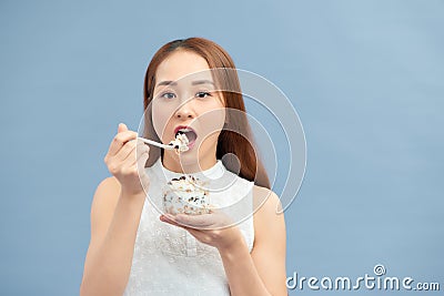 Beautiful young woman eating fresh yoghurt, raisins and oatmeal for breakfast Stock Photo